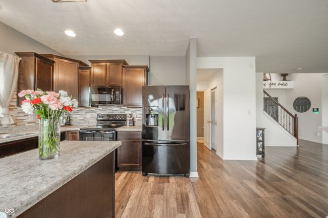 kitchen with black appliances, light wood-type flooring, decorative backsplash, baseboards, and recessed lighting | Image 21
