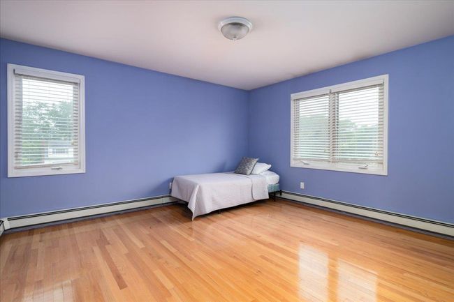 Unfurnished bedroom with baseboard heating, multiple windows, and light wood finished floors | Image 13