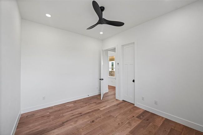 Charming second bedroom with sleek ceiling fan, warm LVP flooring, and ample natural light. Perfect for guests or a cozy home office. | Image 39