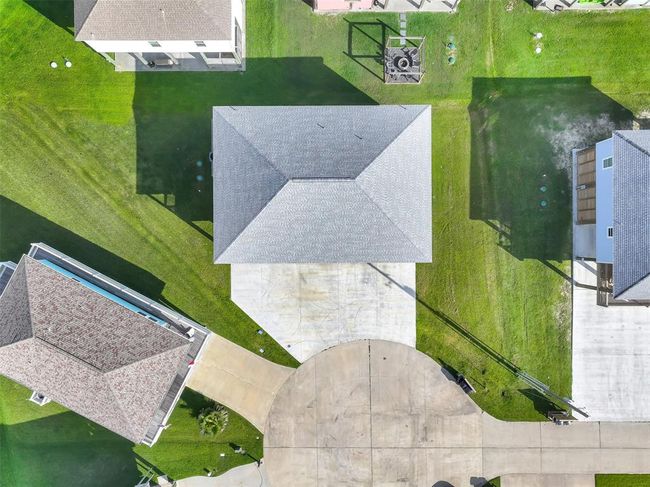 Aerial view of this coastal retreat reveals an oversized driveway, spacious side yard, and peaceful cul-de-sac location just moments from the beach. | Image 31
