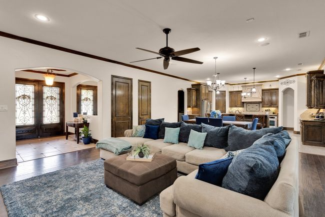 Living room with arched walkways, wood finished floors, ornamental molding, and ceiling fan | Image 8