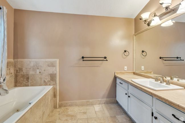 Full bath with baseboards, tiled bath, vanity, and stone finish flooring | Image 10