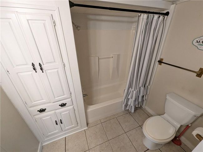 Bathroom with tile patterned floors, toilet, and shower / bathtub combination with curtain | Image 21