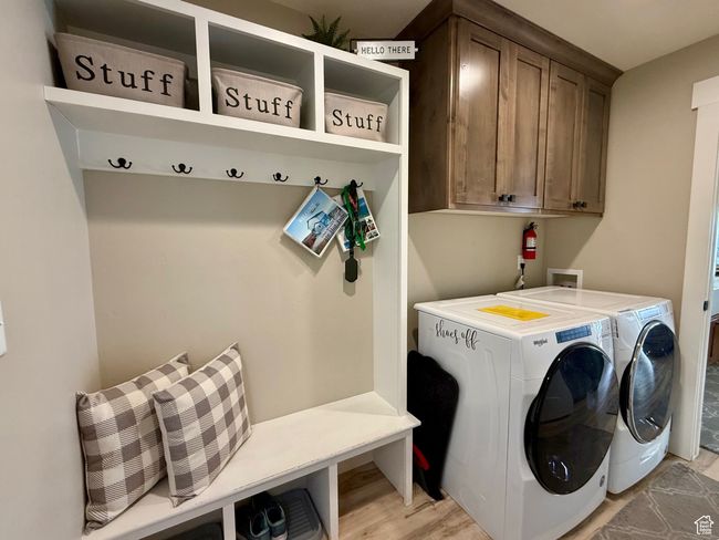 Clothes washing area featuring light wood-type flooring, cabinet space, and independent washer and dryer | Image 35