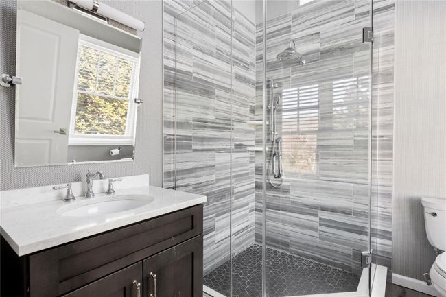 Bathroom with a stall shower, vanity, and toilet | Image 47