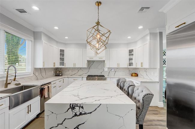 Kitchen featuring appliances with stainless steel finishes, a sink, ornamental molding, hanging light fixtures, and decorative backsplash | Image 7