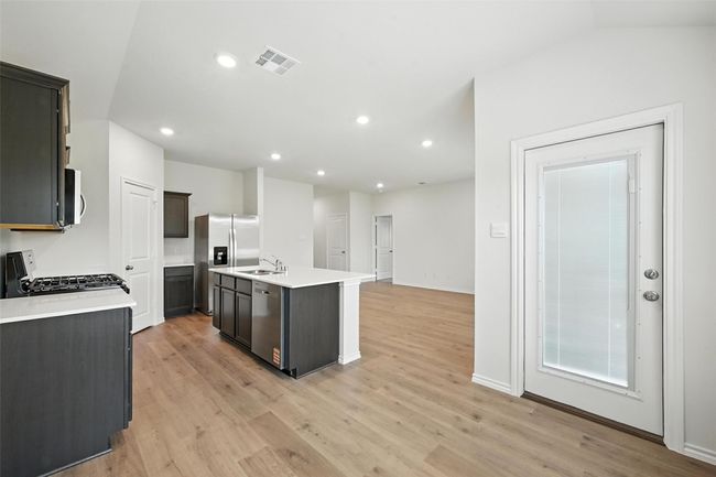 Kitchen featuring appliances with stainless steel finishes, light countertops, a center island with sink, light wood finished floors, and recessed lighting | Image 7