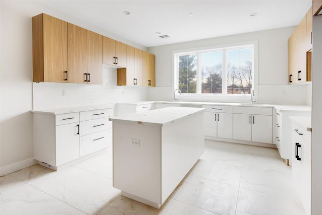 Kitchen with decorative backsplash, a center island, white cabinets, and sink | Image 25
