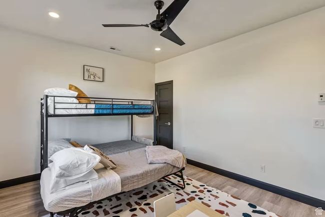 Bedroom with light wood-type flooring, baseboards, and visible vents | Image 49