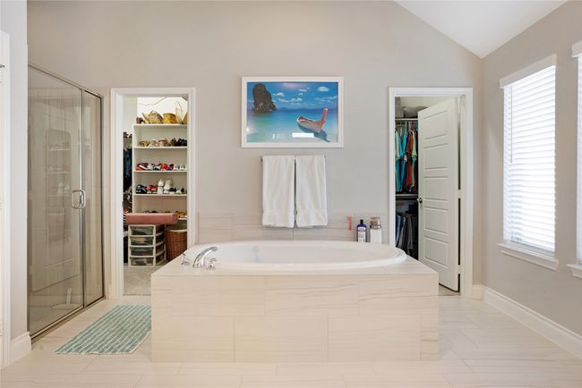 Full bathroom with a spacious closet, a bath, a shower stall, vaulted ceiling, and tile patterned floors | Image 16