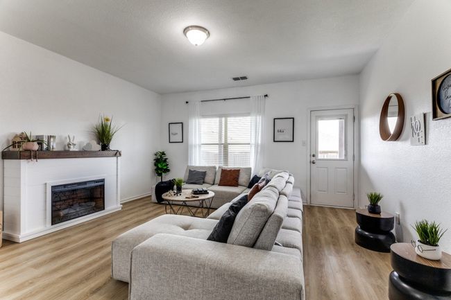 Living room featuring healthy amount of natural light, wood finished floors, and a glass covered fireplace | Image 7