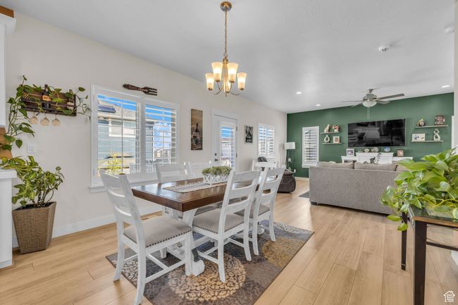 Dining room featuring ceiling fan with notable chandelier, light wood finished floors, and recessed lighting | Image 7