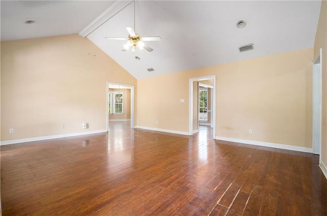 Empty room with ceiling fan, wood finished floors, beam ceiling, and high vaulted ceiling | Image 5