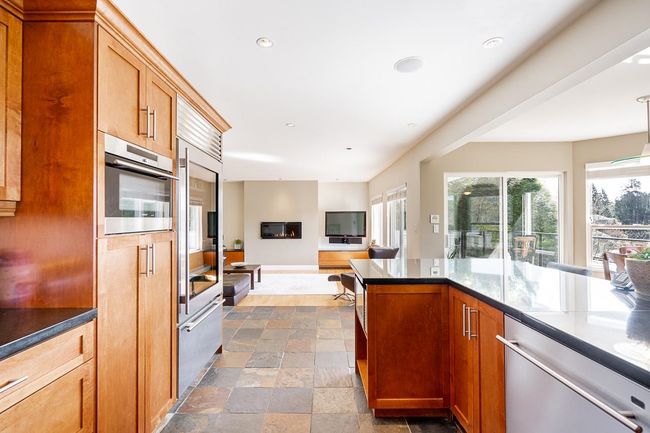 Kitchen with appliances with stainless steel finishes, recessed lighting, dark stone finish flooring, open floor plan, and brown cabinets | Image 12