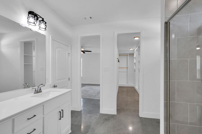 Bathroom featuring vanity, a tile shower, concrete flooring, a walk in closet, and a ceiling fan | Image 31