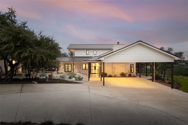 Front view of house with a standing seam roof, stone, siding, metal roof, concrete driveway, and a carport | Image 8