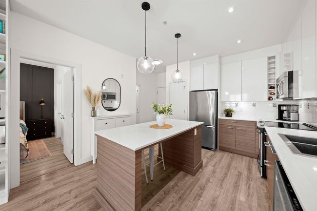 Kitchen featuring a breakfast bar area, stainless steel appliances, modern cabinets, and light wood-style flooring | Image 10