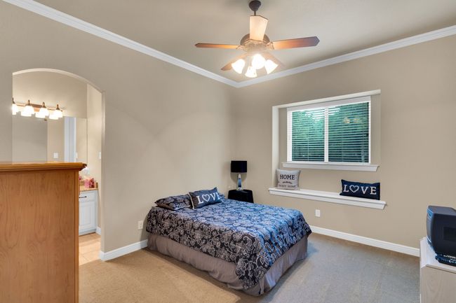 Bedroom with carpet, ornamental molding, ensuite bathroom, arched walkways, and a ceiling fan | Image 26