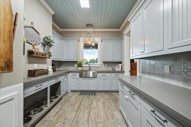 This bright and spacious laundry room offers a relaxing view, with a large window above the sink that overlooks the back patio and serene pond. Watch the wildlife while you work, adding a peaceful touch to your chores. | Image 25