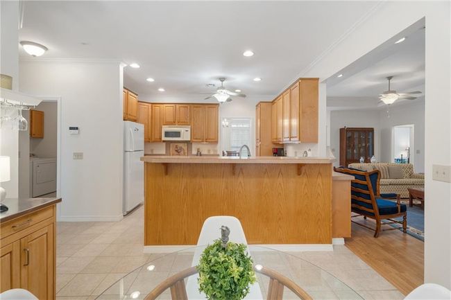 Kitchen featuring washer / clothes dryer, a ceiling fan, white appliances, and a peninsula | Image 24