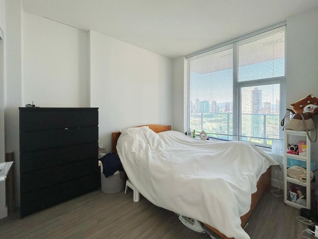 Bedroom featuring wood finished floors, expansive windows, and a city view | Image 9