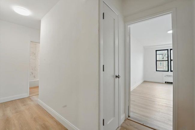 Hall featuring light wood-style flooring, baseboards, and radiator | Image 17
