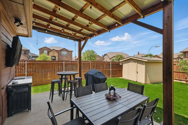 View of patio / terrace featuring a storage shed, a fenced backyard, outdoor dining space, and an outbuilding | Image 30