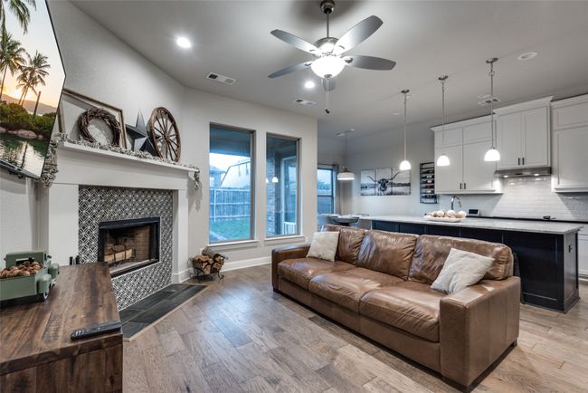 Living room with light wood finished floors, a tile fireplace, visible vents, and a ceiling fan | Image 12