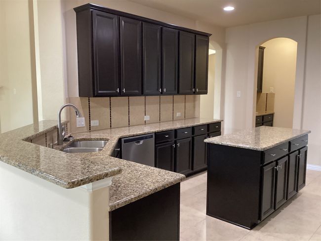 Kitchen featuring dishwashing machine, a sink, arched walkways, a peninsula, and dark cabinets | Image 7