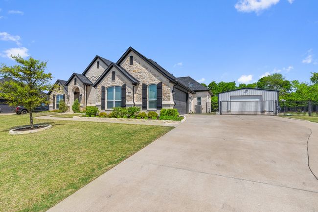 French country home featuring an outdoor structure, stone siding, a front yard, and fence | Image 4