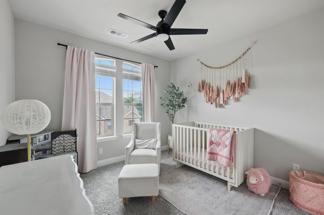 Carpeted bedroom with a ceiling fan, a nursery area, baseboards, and visible vents | Image 18