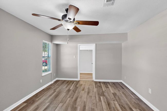 Empty room with wood finished floors and a ceiling fan | Image 4