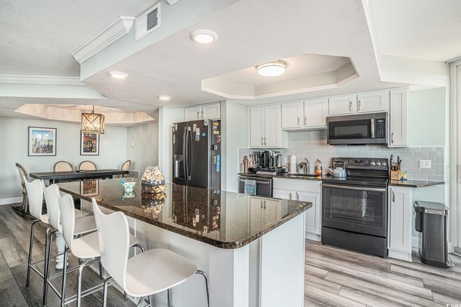 Kitchen with appliances with stainless steel finishes, light wood-style flooring, a breakfast bar, white cabinets, and recessed lighting | Image 11