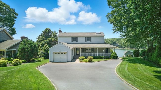 View of front of home featuring covered porch, driveway, a front lawn, an attached garage, and solar panels | Image 5