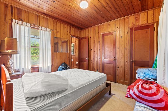 Bedroom with wooden walls, wood ceiling, and carpet | Image 20
