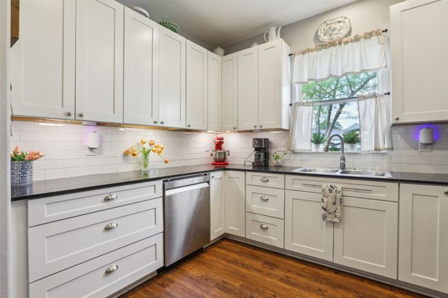 Kitchen with a sink, backsplash, Corian countertops, dishwasher, and wood plank laminate flooring | Image 15