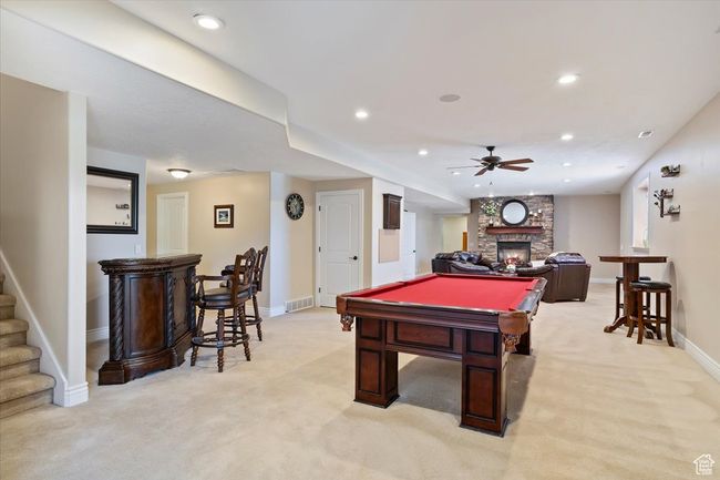 Recreation room with light carpet, baseboards, a stone fireplace, ceiling fan, and billiards | Image 19