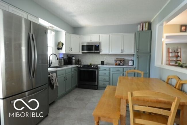 kitchen featuring white cabinets, stainless steel appliances, a sink, backsplash, and light countertops | Image 26