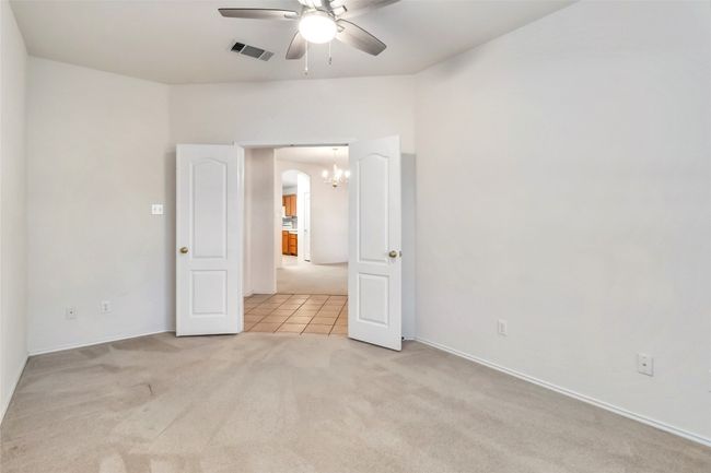 Unfurnished bedroom featuring carpet floors, arched walkways, tile patterned floors, a chandelier, and a ceiling fan | Image 10
