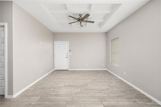 Empty room featuring coffered ceiling, ceiling fan, light wood-style flooring, and beamed ceiling | Image 8