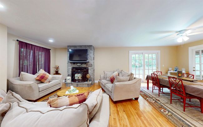 Living room featuring plenty of natural light, light wood-type flooring, recessed lighting, ceiling fan, and a stone fireplace | Image 9