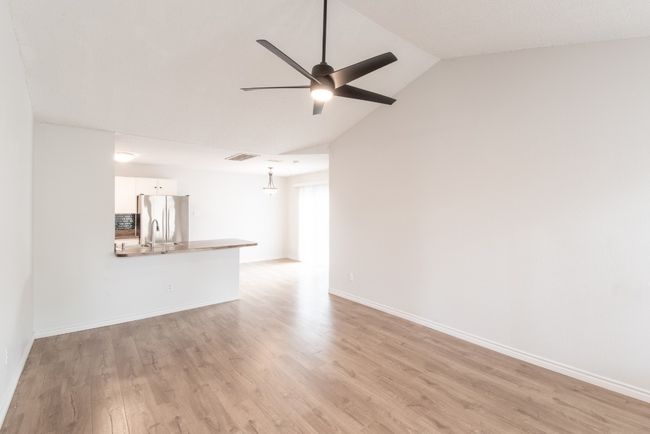 Unfurnished living room with a ceiling fan, light wood-style flooring, and lofted ceiling | Image 7