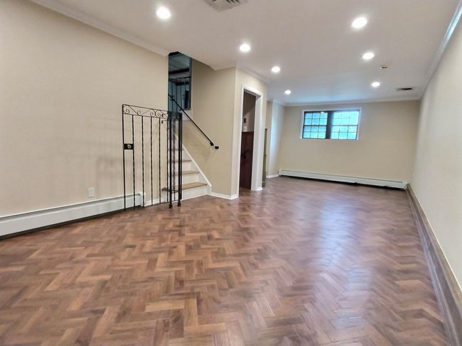 Spare room featuring a baseboard heating unit, baseboards, ornamental molding, recessed lighting, and stairway | Image 23