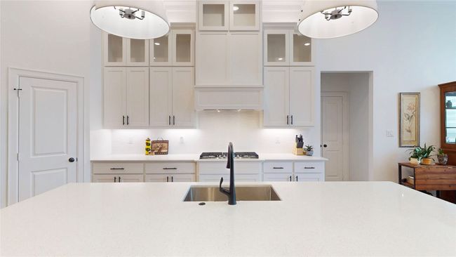 Kitchen with light countertops, white cabinets, hanging light fixtures, and stainless steel gas stovetop | Image 12