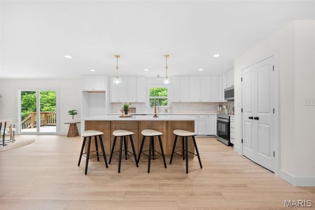 Kitchen featuring stainless steel appliances, a center island, recessed lighting, light wood-style flooring, and white cabinetry | Image 13