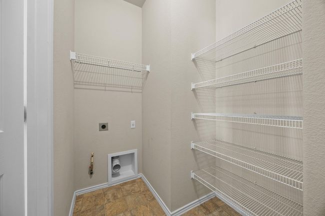 Washroom with stone finish flooring, hookup for an electric dryer, gas dryer hookup, laundry area, and baseboards | Image 15