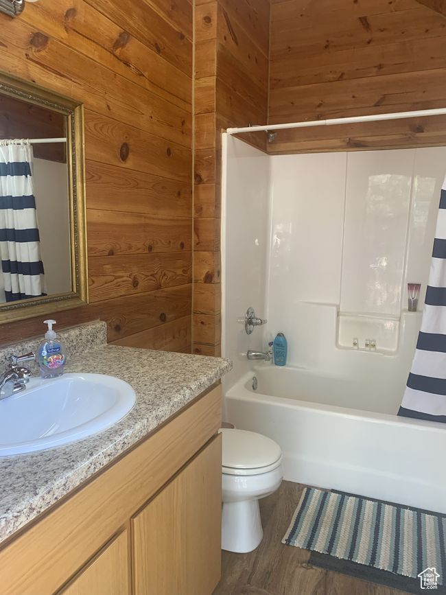 Full bathroom featuring vanity, toilet, shower / bath combo, and wooden walls | Image 30