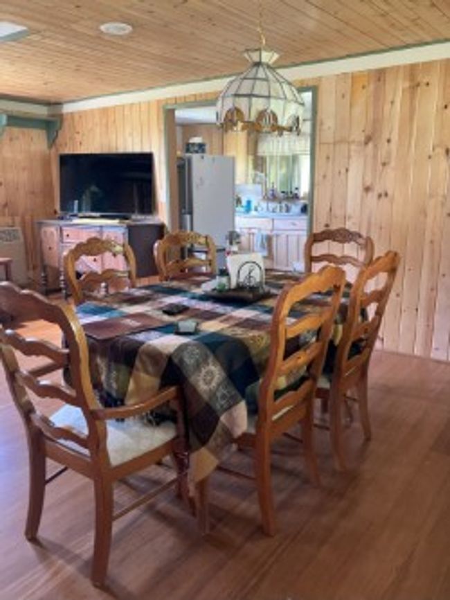 Dining room featuring wooden walls, wooden ceiling, a chandelier, and wood finished floors | Image 28