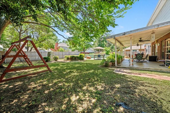 View of the backyard with expansive covered patio, sparkling pool and "grotto-style" hot tub, as well as plenty of grassy area for your resident pooch to enjoy. | Image 10