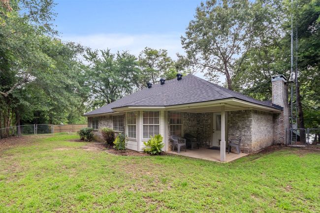 Back of property featuring a chimney, a patio, a fenced backyard, roof with shingles, and a gate; internet antenna installed for better reception. | Image 24
